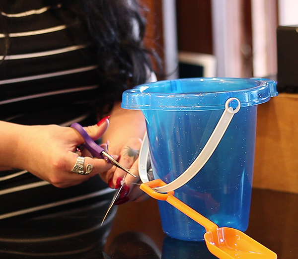 A woman cutting the hang tag off of a beach bucket - Image by MCM